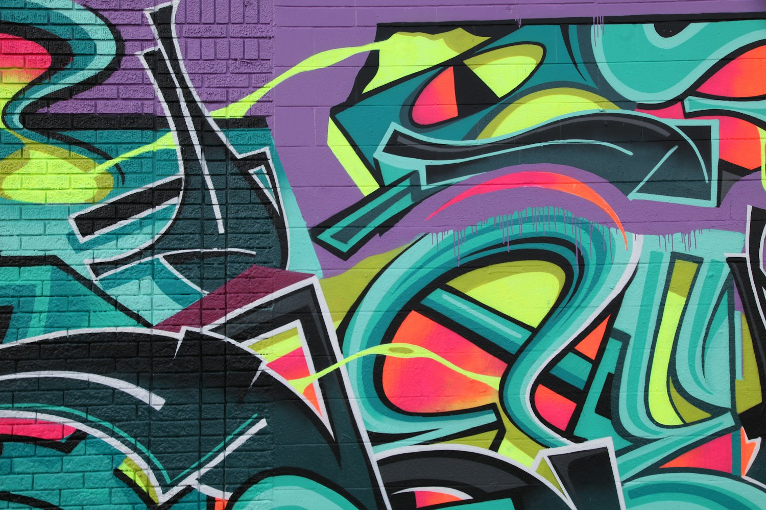 Tag e graffiti dai colori vivaci appena spruzzati su un muro.